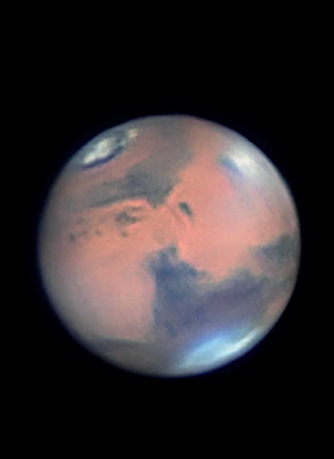 Fotografie a planetei Marte. Imaginea arată clar norii din zona marelui vulcan-scut Elysium Mons. Calota polară nordică puternic topită se vede, de asemenea, foarte bine. Mario Weigand