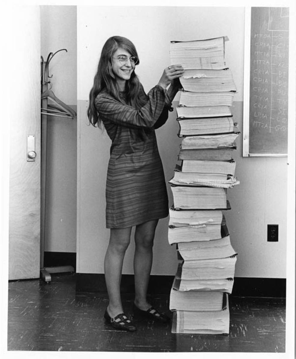 Margaret Hamilton lângă un teanc de coduri sursă ale Apollo Guidance Computer. © Courtesy MIT Museum